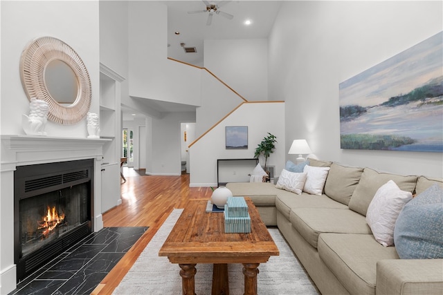 living room with ceiling fan, hardwood / wood-style floors, and a towering ceiling