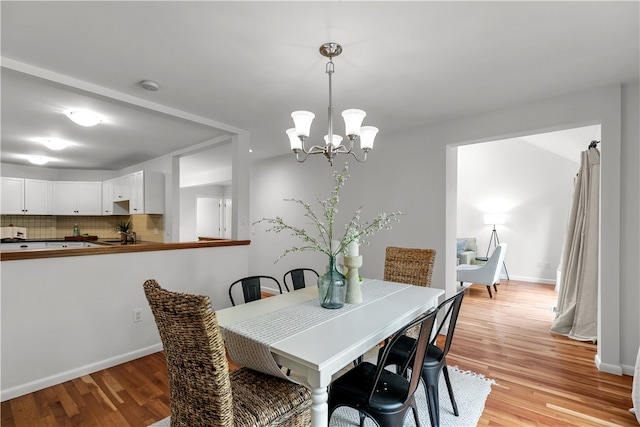 dining area with light hardwood / wood-style floors and an inviting chandelier