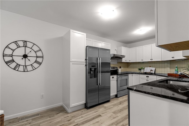 kitchen featuring appliances with stainless steel finishes, white cabinetry, dark stone counters, tasteful backsplash, and sink