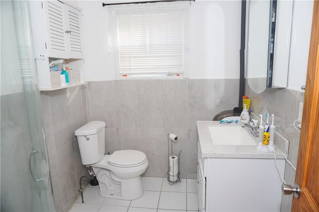 bathroom featuring tile walls, vanity, toilet, a shower with door, and tile patterned floors