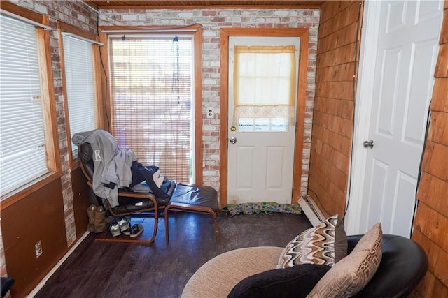 foyer entrance with a baseboard radiator, brick wall, and hardwood / wood-style floors