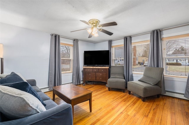 living room featuring light hardwood / wood-style floors, a baseboard radiator, a textured ceiling, and ceiling fan