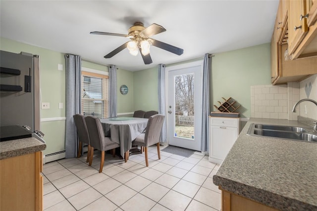 dining space with sink, a baseboard radiator, light tile patterned floors, and ceiling fan