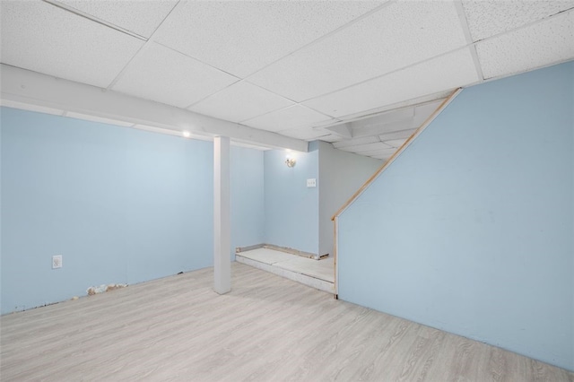 basement with light hardwood / wood-style floors and a paneled ceiling