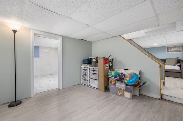 basement featuring light hardwood / wood-style floors and a paneled ceiling