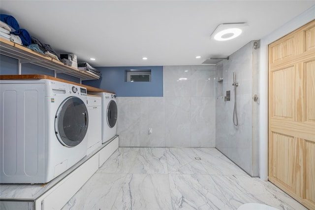 clothes washing area featuring tile walls and washing machine and clothes dryer