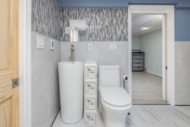 bathroom with a paneled ceiling, toilet, and gas water heater