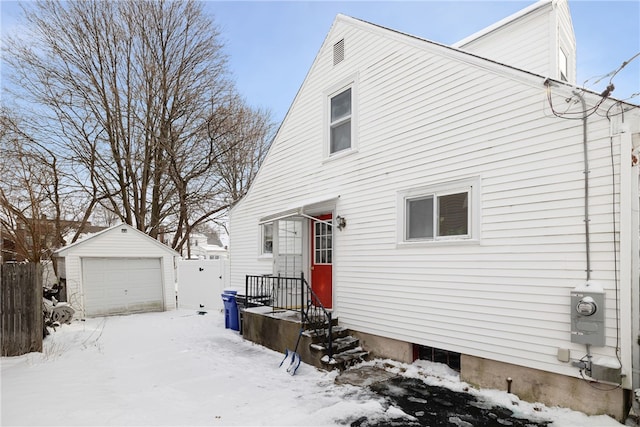 snow covered property with a garage and an outbuilding