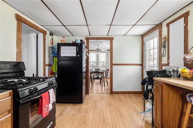 kitchen with black appliances, light hardwood / wood-style flooring, and a paneled ceiling