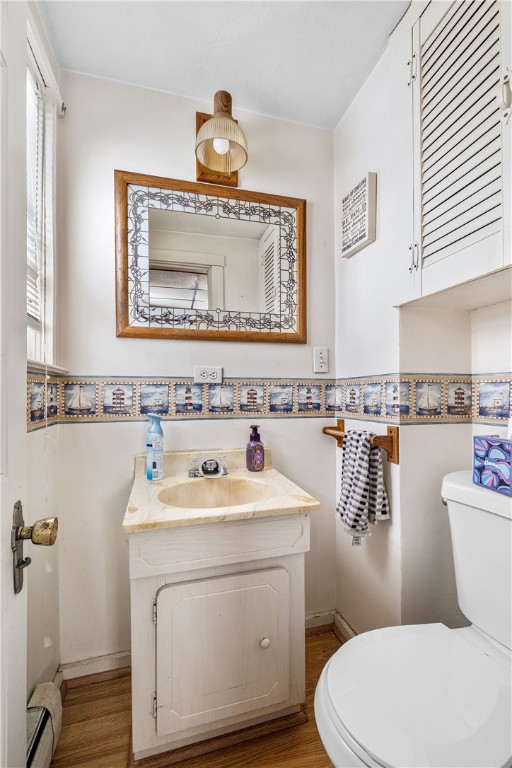 bathroom featuring vanity, toilet, baseboard heating, and wood-type flooring