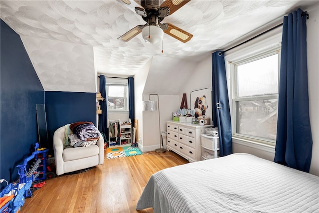 bedroom with ceiling fan, hardwood / wood-style floors, and lofted ceiling