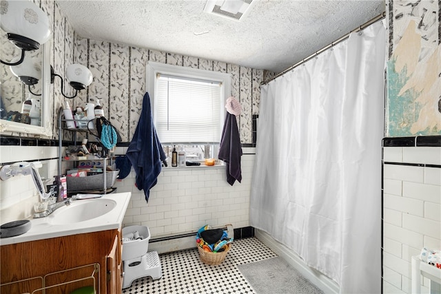 bathroom with baseboard heating, a textured ceiling, walk in shower, and vanity