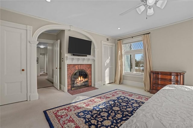 bedroom with crown molding, a brick fireplace, light colored carpet, and ceiling fan