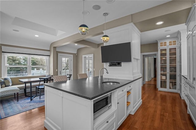 kitchen featuring white cabinetry, stainless steel microwave, decorative light fixtures, and sink