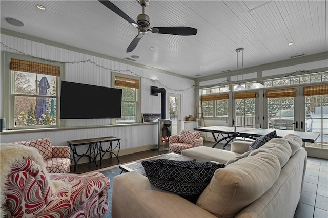 living room with light tile patterned floors, wooden ceiling, ceiling fan, and a wood stove