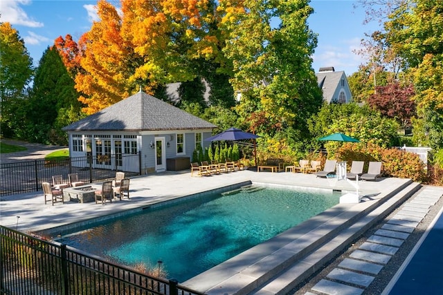 view of swimming pool featuring an outdoor structure, a patio, and an outdoor fire pit