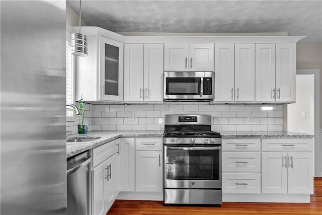 kitchen with decorative light fixtures, light hardwood / wood-style floors, white cabinetry, and stainless steel appliances