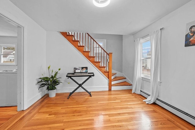 foyer entrance featuring a baseboard heating unit and light wood-type flooring