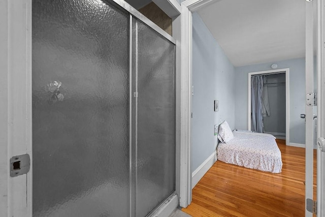 bathroom with wood-type flooring and a shower with door