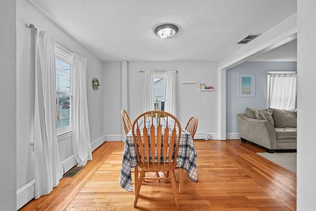 dining space featuring light hardwood / wood-style flooring and a baseboard heating unit