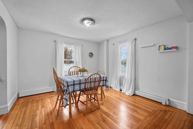 dining room featuring a baseboard heating unit and light hardwood / wood-style floors