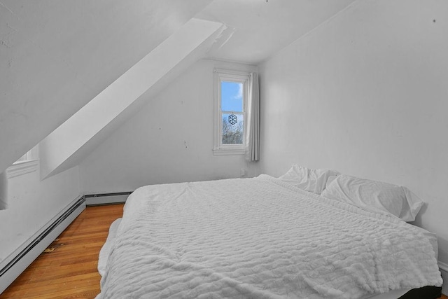 bedroom featuring hardwood / wood-style flooring, a baseboard radiator, and vaulted ceiling