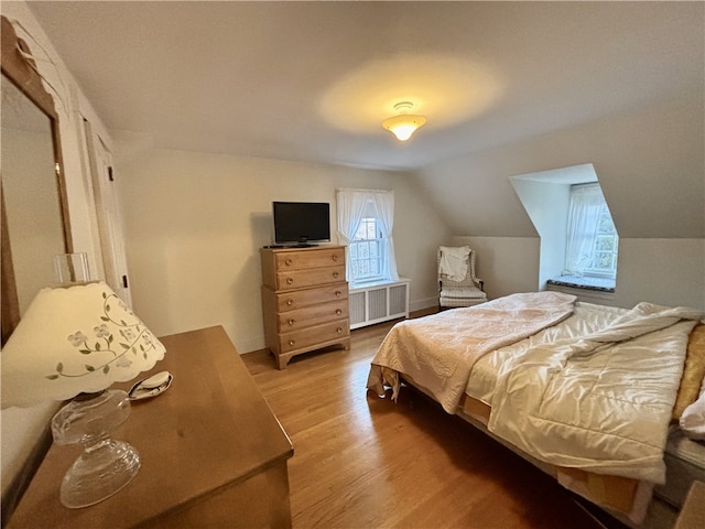 bedroom with hardwood / wood-style floors, radiator, and vaulted ceiling