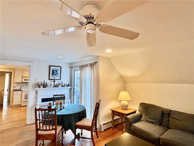 dining space featuring a baseboard radiator, light hardwood / wood-style floors, vaulted ceiling, and ceiling fan