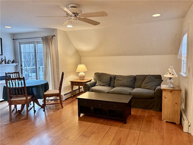 living room with light hardwood / wood-style floors, a baseboard radiator, ceiling fan, and vaulted ceiling