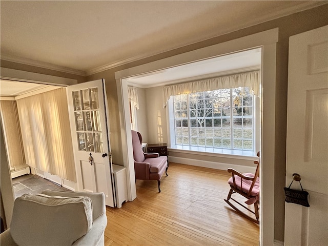 sitting room featuring baseboard heating, hardwood / wood-style floors, and ornamental molding