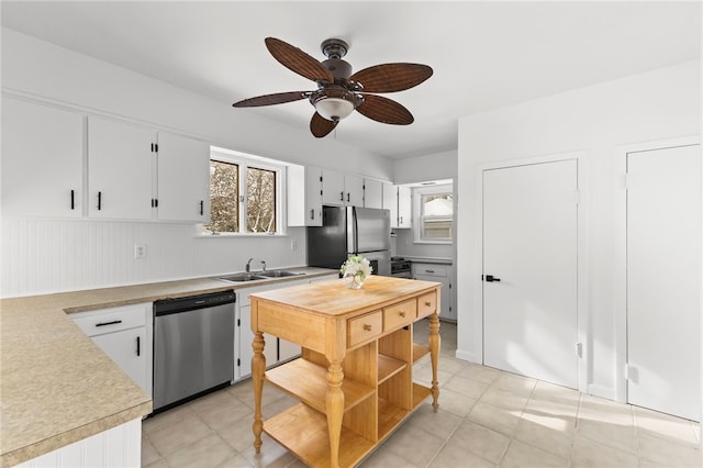 kitchen with white cabinets, stainless steel appliances, light tile patterned floors, and sink