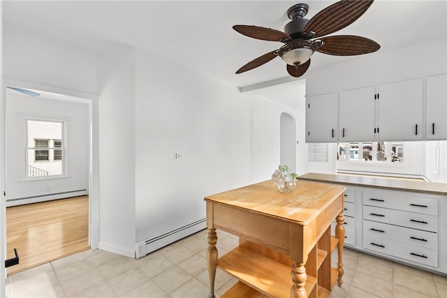 kitchen featuring ceiling fan, white cabinets, a baseboard heating unit, and light tile patterned floors