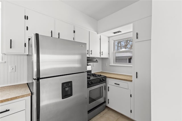 kitchen with ventilation hood, white cabinetry, light tile patterned floors, and appliances with stainless steel finishes