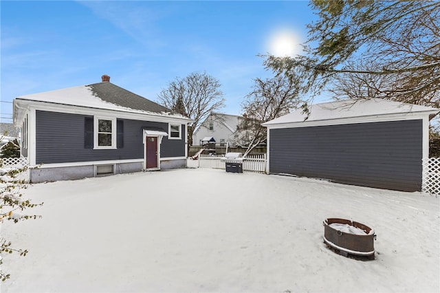 snow covered rear of property with a fire pit