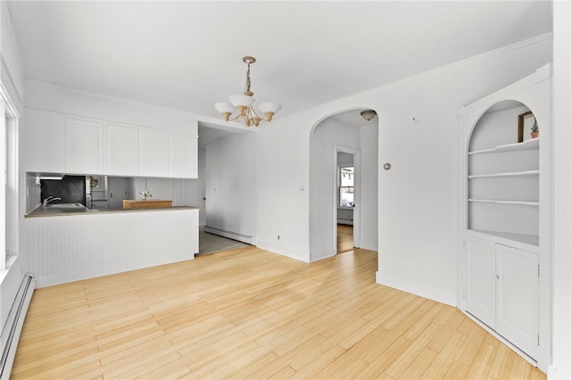 interior space with white cabinets, kitchen peninsula, a baseboard heating unit, and built in features