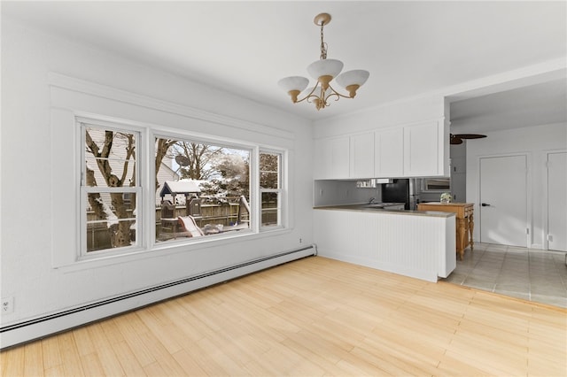 kitchen with baseboard heating, light hardwood / wood-style flooring, stainless steel fridge, hanging light fixtures, and white cabinetry