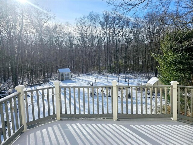 snow covered deck featuring a storage shed