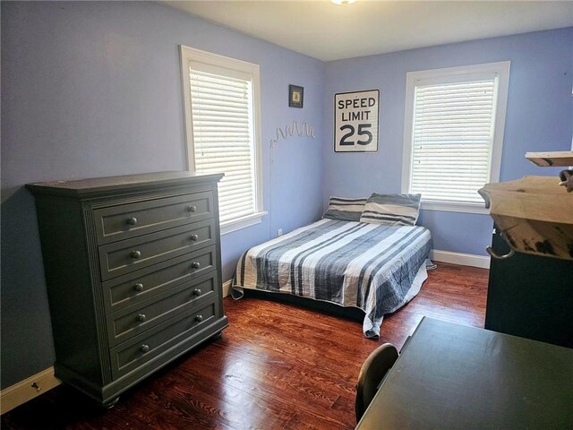 bedroom with dark wood-type flooring and multiple windows