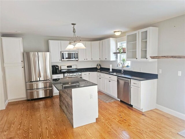 kitchen with light hardwood / wood-style flooring, hanging light fixtures, appliances with stainless steel finishes, sink, and white cabinetry