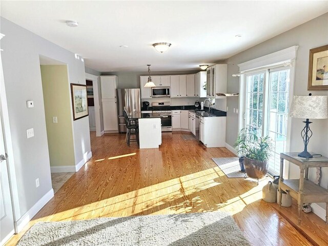 kitchen featuring a center island, appliances with stainless steel finishes, hanging light fixtures, white cabinets, and sink