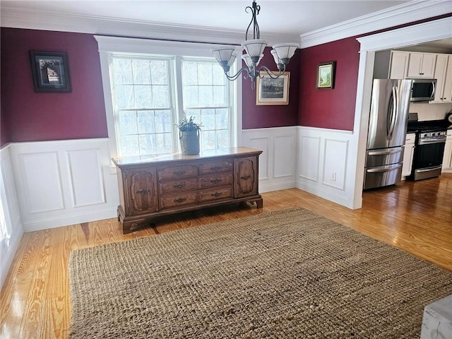 dining space with a notable chandelier, hardwood / wood-style flooring, and ornamental molding