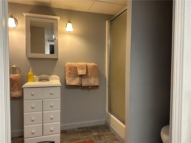 full bathroom featuring vanity, toilet, enclosed tub / shower combo, and a drop ceiling