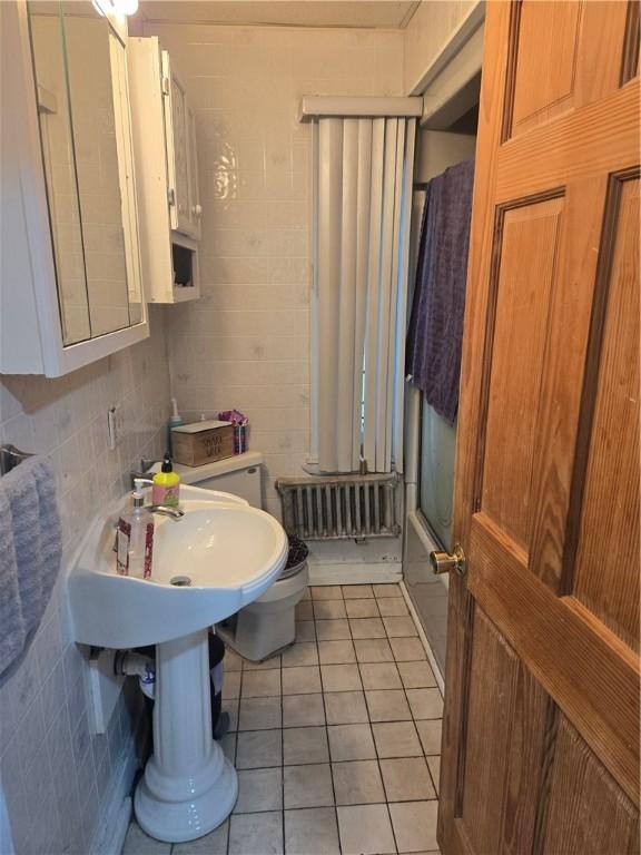 bathroom with radiator heating unit, tile patterned flooring, and enclosed tub / shower combo