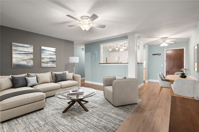 living room featuring decorative columns, ceiling fan, and hardwood / wood-style floors