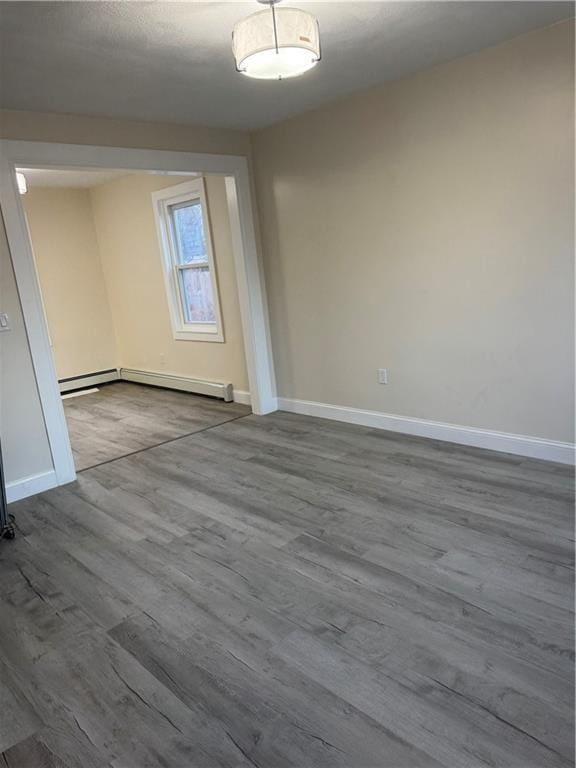 unfurnished room with hardwood / wood-style floors and a baseboard heating unit