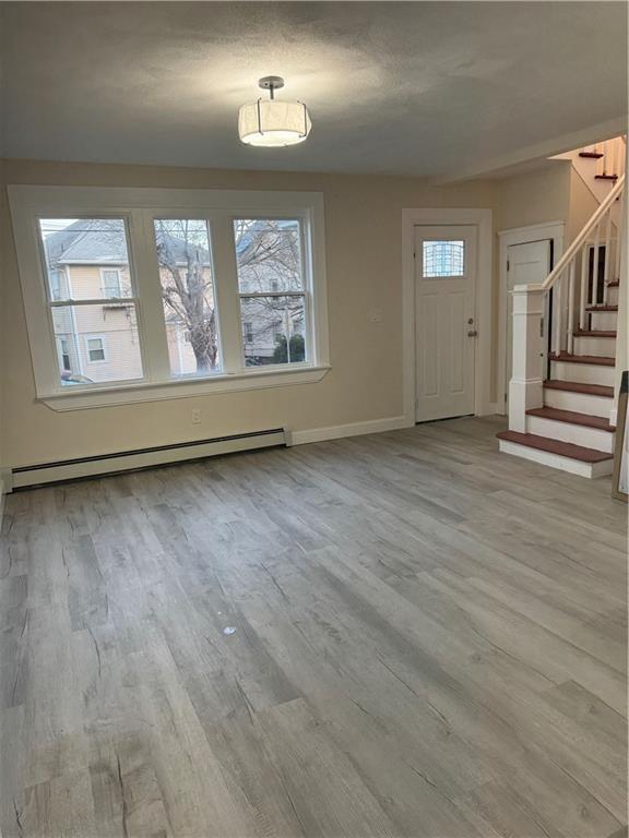 foyer featuring baseboard heating, light wood-type flooring, and a wealth of natural light