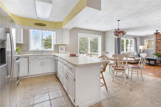 kitchen featuring appliances with stainless steel finishes, kitchen peninsula, hanging light fixtures, and white cabinets