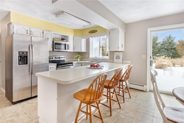 kitchen with white cabinetry, sink, a breakfast bar area, kitchen peninsula, and stainless steel appliances