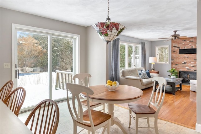 dining room featuring a brick fireplace and ceiling fan