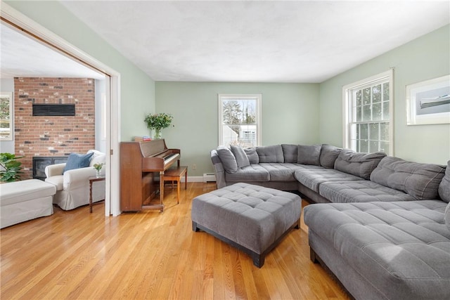 living room with a brick fireplace, a wealth of natural light, baseboard heating, and light wood-type flooring